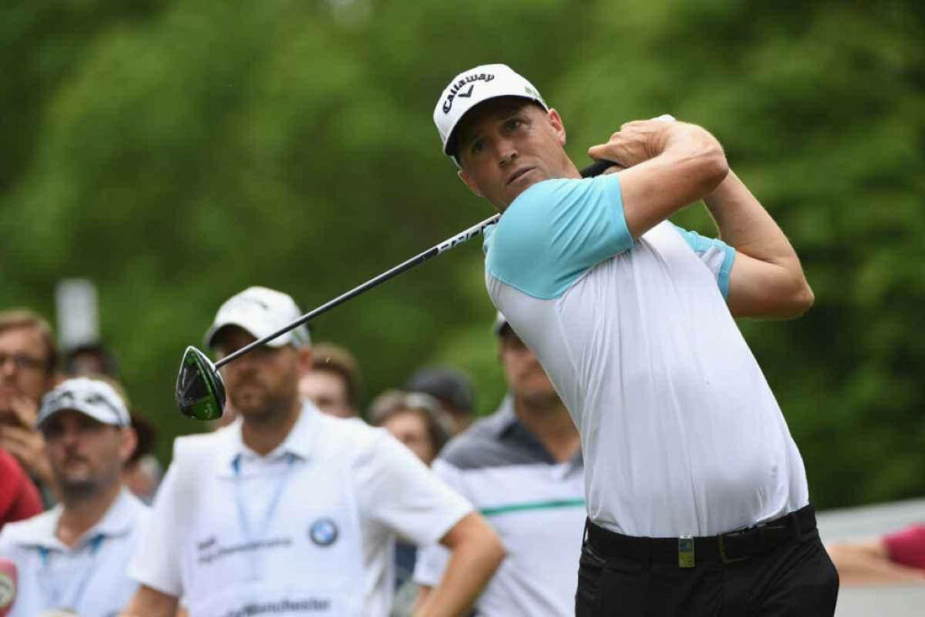 Alex Norén swinging golf club at tournament with attentive audience on lush green course background Wallpaper