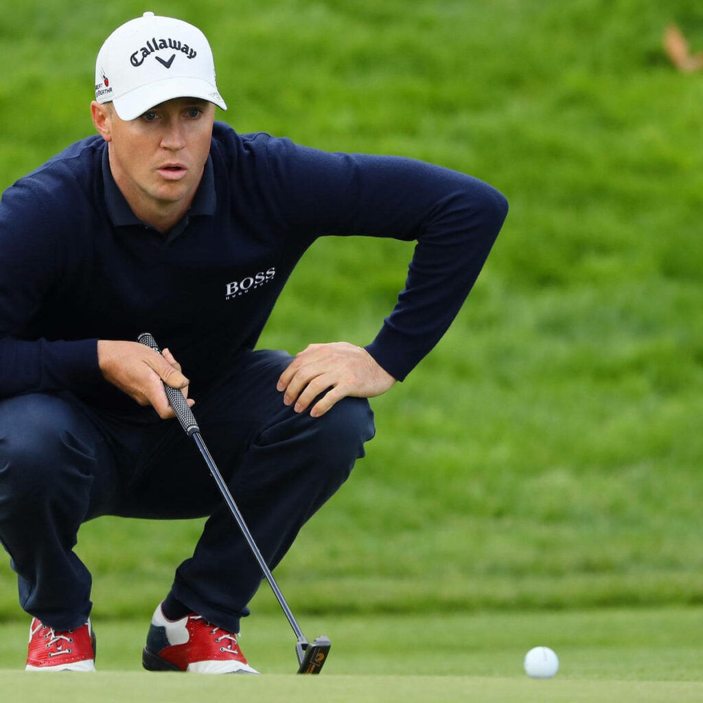 Alex Norén crouching on golf course lining up precise putt focused in professional golf setting Wallpaper