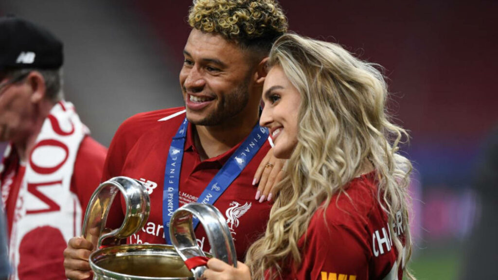 Alex Oxlade-Chamberlain and Perrie Edwards smiling celebrating in red holding trophy wallpaper