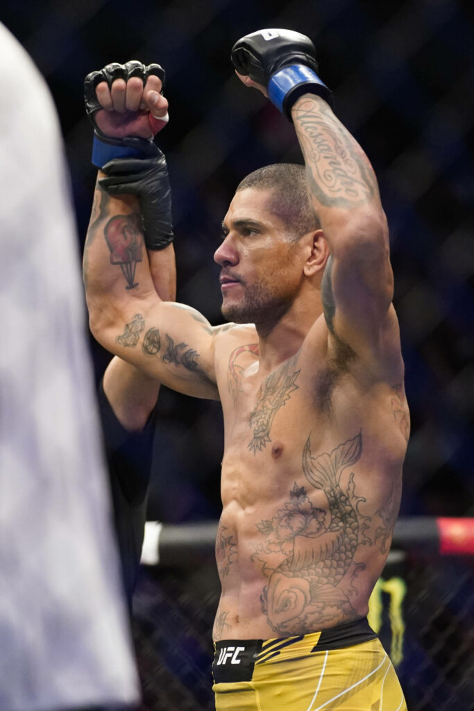 Alex Pereira celebrates UFC victory raising fists in octagon showing tattoos with wallpaper background