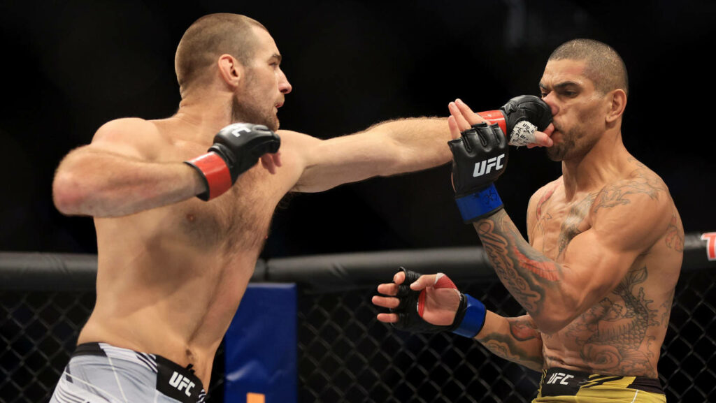 Alex Pereira lands a powerful punch breaking opponent's guard in intense UFC fight wallpaper