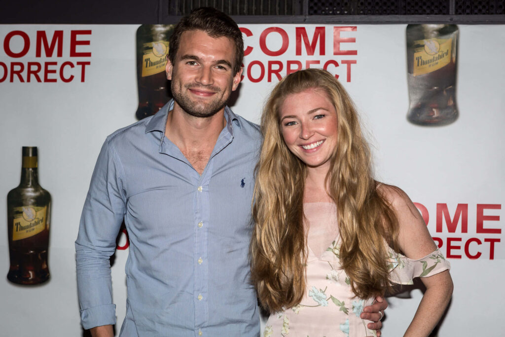 Alex Russell and guest smiling warmly at event creating cheerful inviting wallpaper background