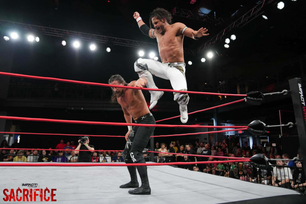 Alex Shelley delivers intense aerial attack against Seth Collins in Sacrifice wrestling match crowd watching Wallpaper
