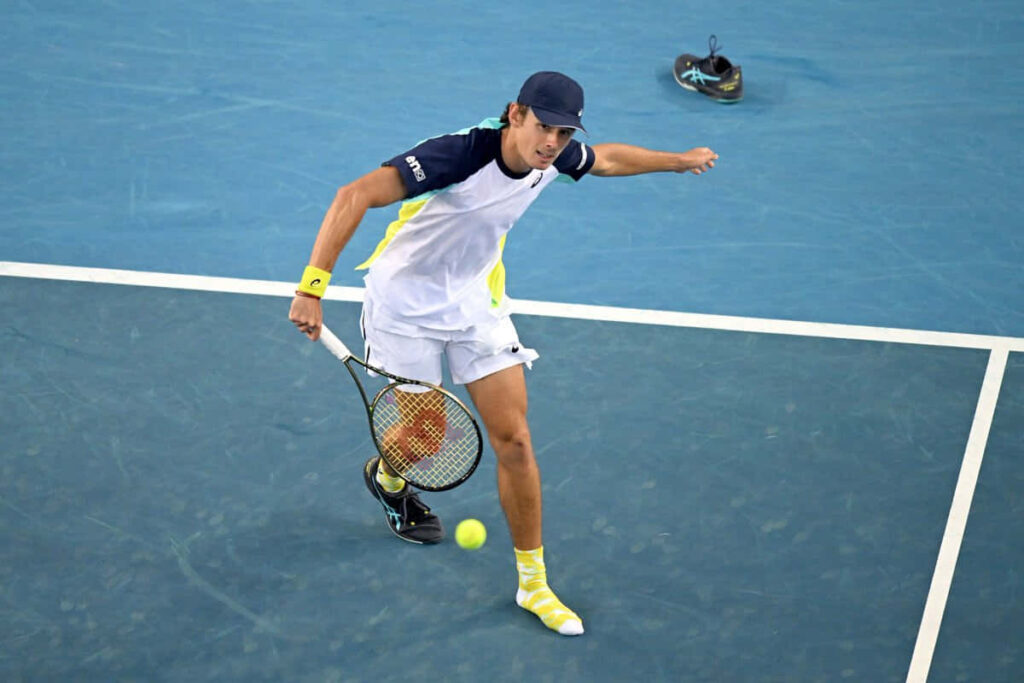 Alex de Minaur focused hitting backhand tennis shot during intense match wallpaper background