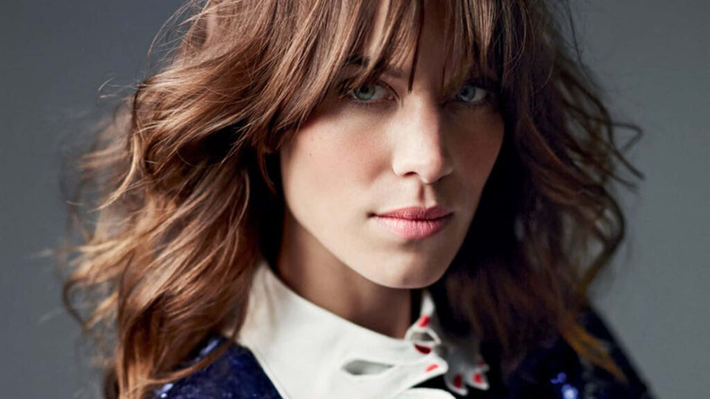 Portrait of Alexa Chung with intense gaze and effortless style on soft blurred wallpaper background