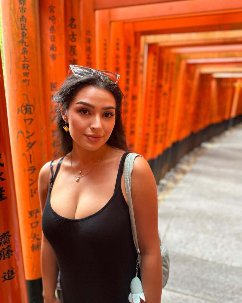 Alexa Rose Steele amid vibrant orange torii gates at Fushimi Inari Taisha Shrine wallpaper background