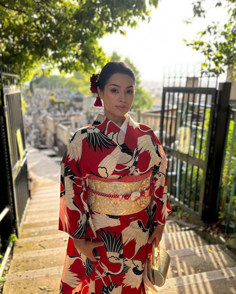Alexa Rose Steele in elegant red crane kimono on sunlit stone steps with serene outdoor background Wallpaper