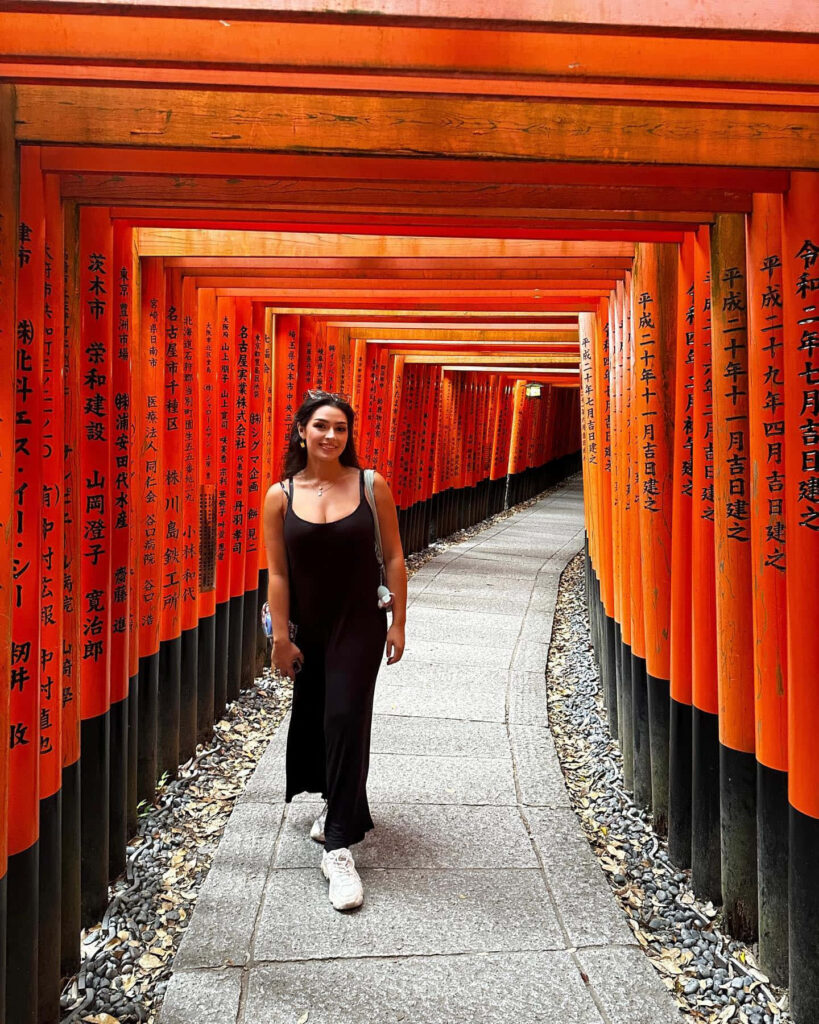 Alexa Rose Steele walking through vibrant red Torii gates at Fushimi Inari Taisha Japan wallpaper