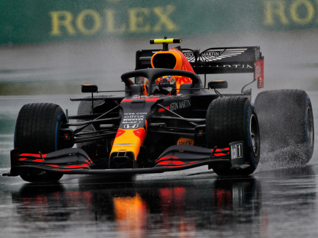 Alexander Albon driving Aston Martin Red Bull Racing car on wet track with water spray background Wallpaper