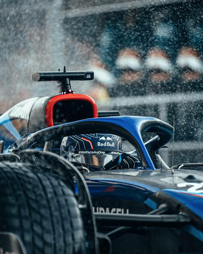 Alexander Albon racing Formula 1 car on rain-soaked track with dramatic water spray background Wallpaper