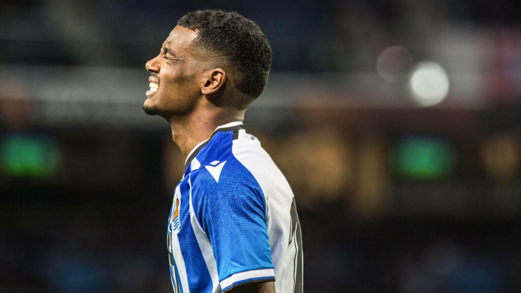 Side view of Alexander Isak in blue white jersey showing intense focus and energy on field Wallpaper