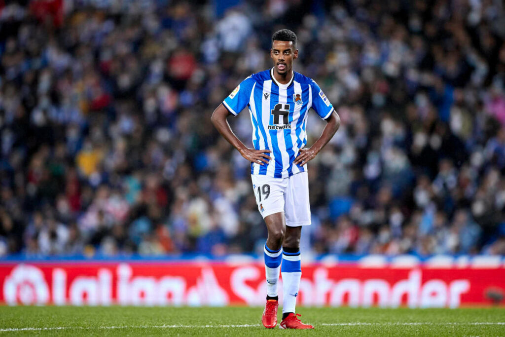Alexander Isak walking on football field in Real Sociedad kit focused game atmosphere background Wallpaper