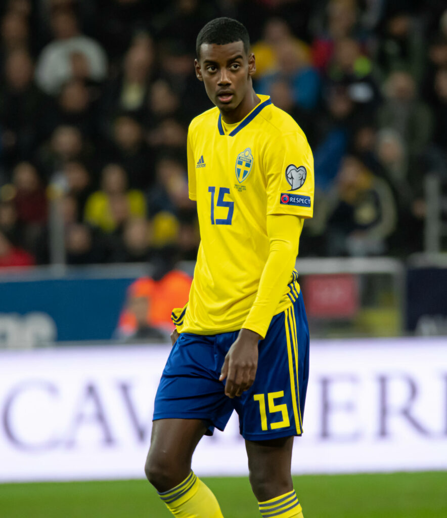 Alexander Isak in Swedish national football kit walking on field during intense match wallpaper background