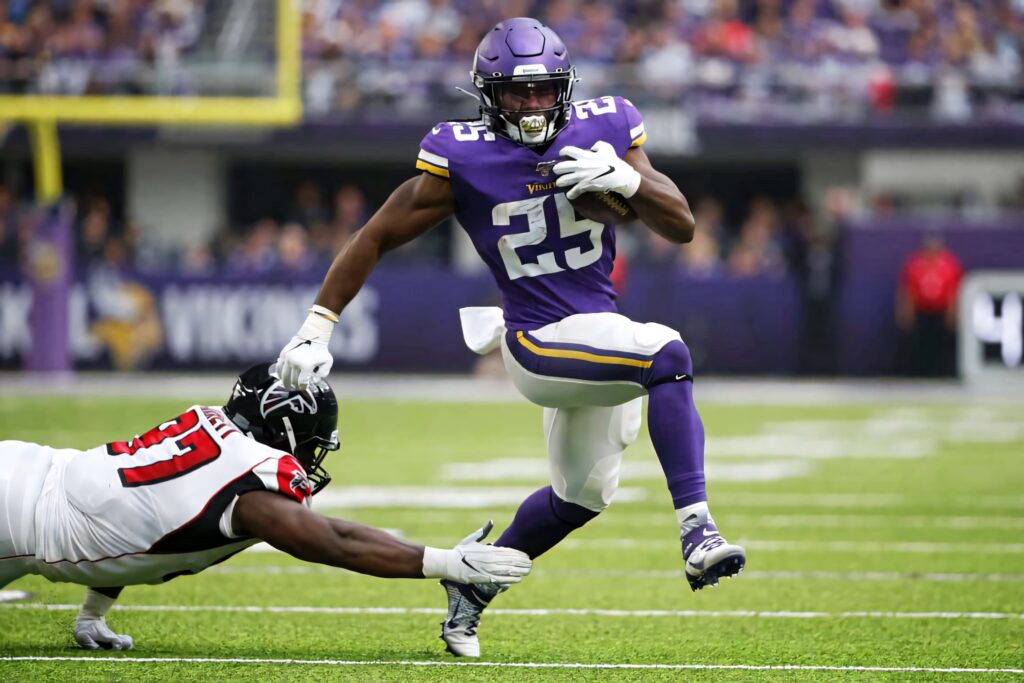 Alexander Mattison dodges tackle showcasing agility and power in dynamic football action wallpaper