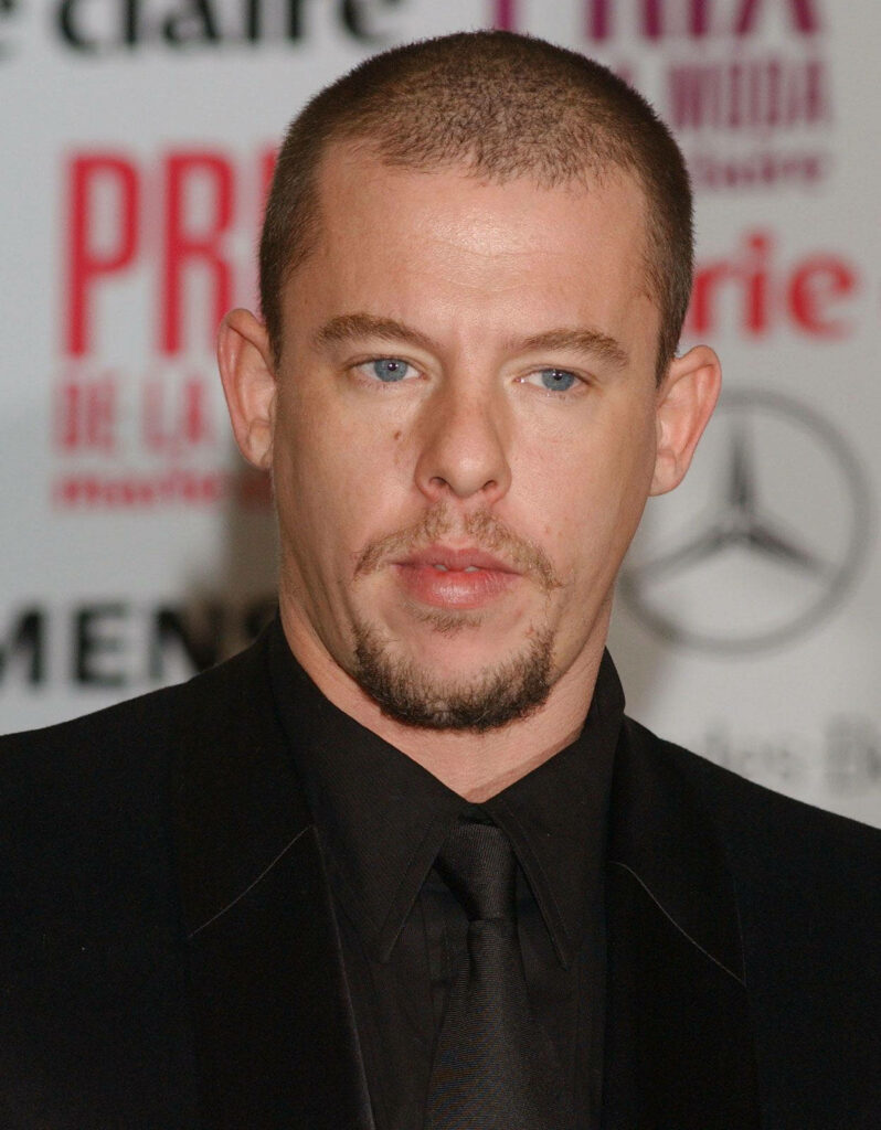 Alexander McQueen in sharp black suit at Mercedes launch event with branded wallpaper backdrop