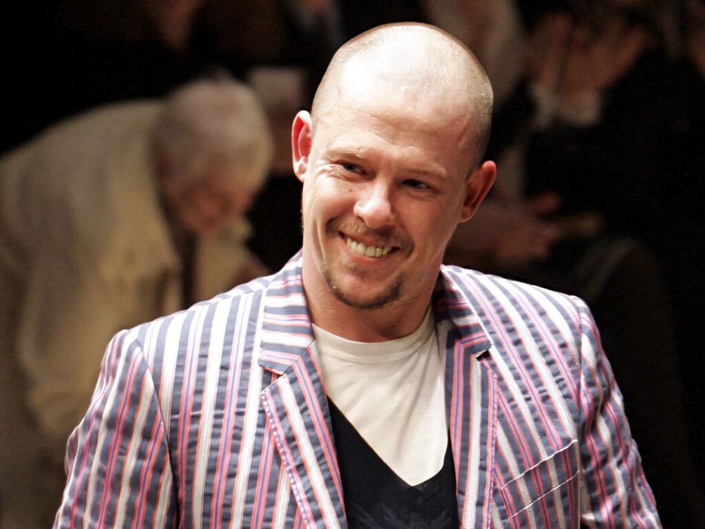 Alexander McQueen smiling on runway wearing colorful striped jacket bold iconic fashion style Wallpaper
