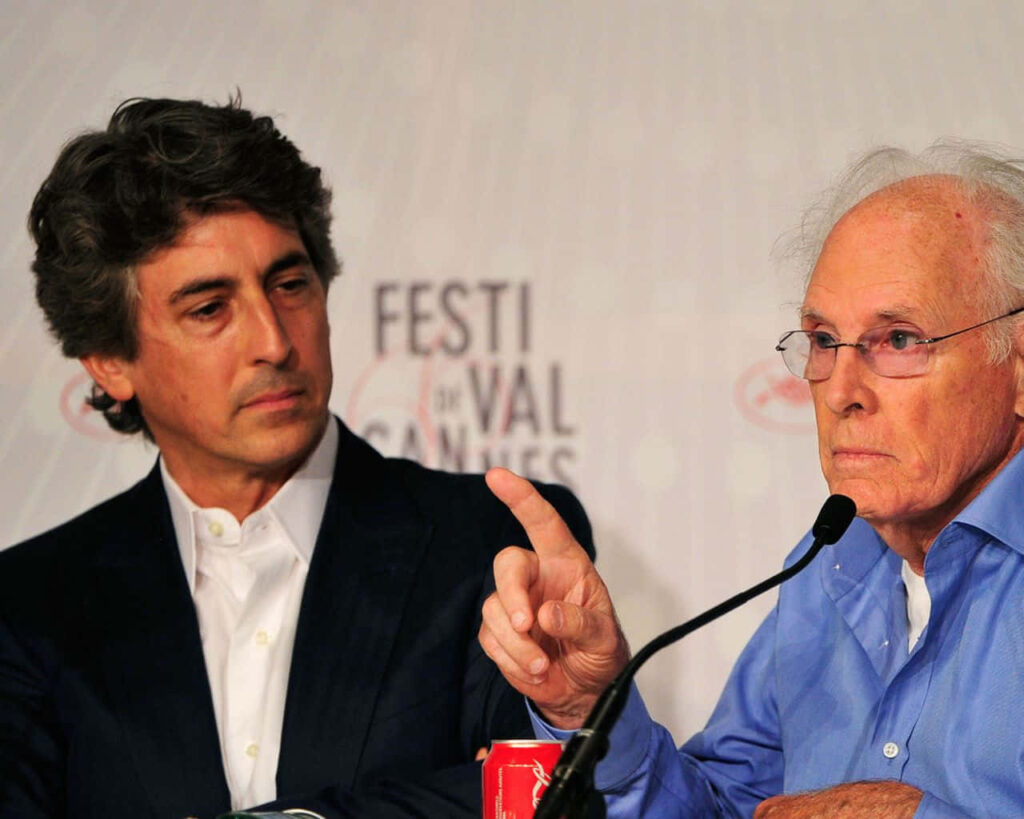 Director Alexander Payne and actor Bruce Dern speaking at a press event with elegant backdrop Wallpaper