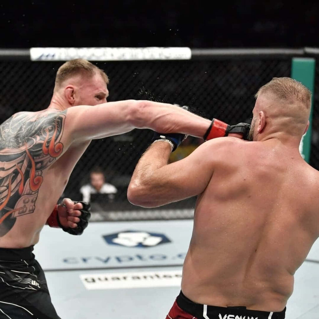 Alexander Volkov lands a powerful punch in octagon MMA fight intense action wallpaper background