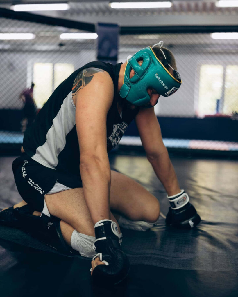 Exhausted Alexander Volkov kneeling on gym mat wearing boxing gloves and headgear during training Wallpaper