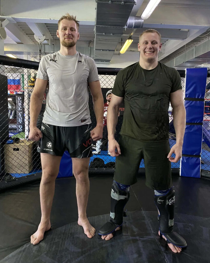 Alexander Volkov and athlete training inside MMA gym cage showing focus and determination Wallpaper
