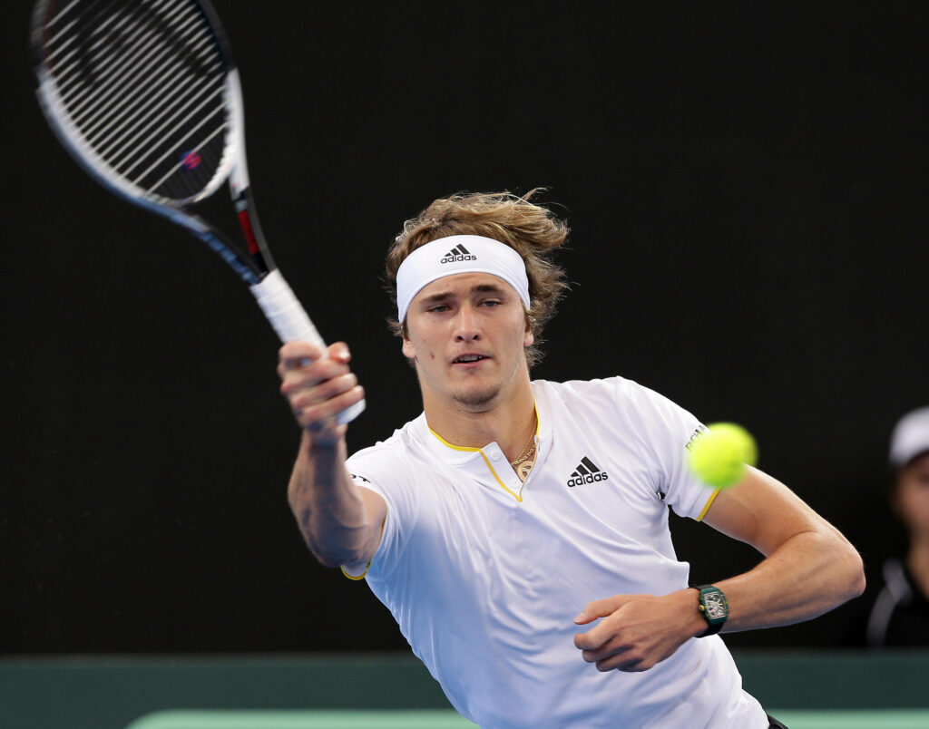 Alexander Zverev hitting powerful forehand volley in intense tennis match on court background Wallpaper