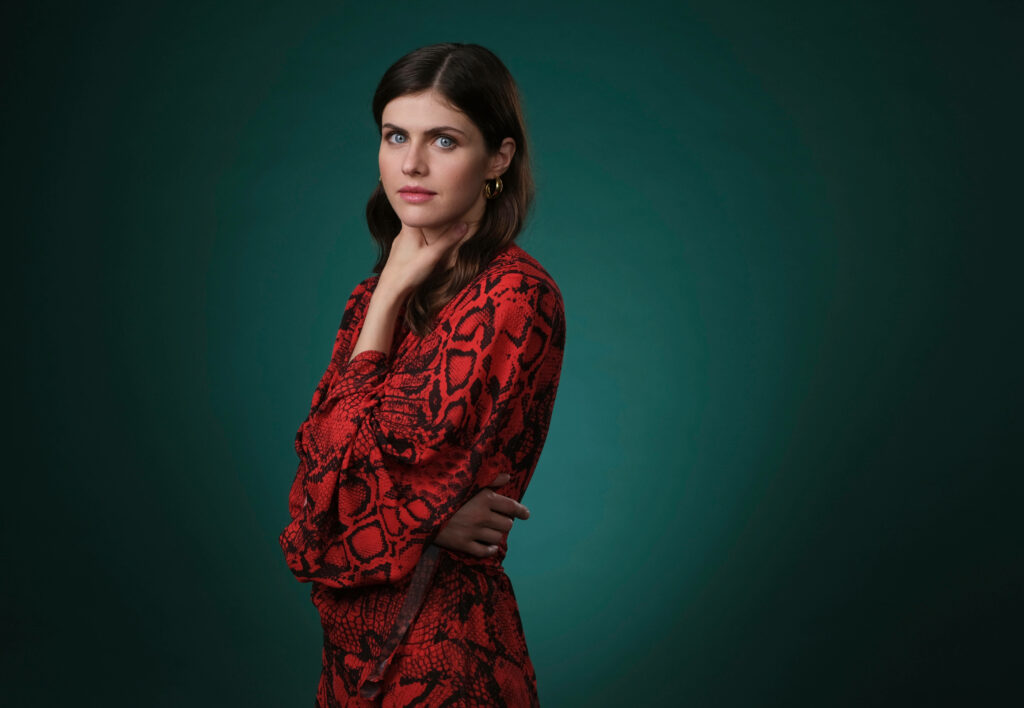 Alexandra Daddario in red patterned outfit against emerald green background stylish wallpaper