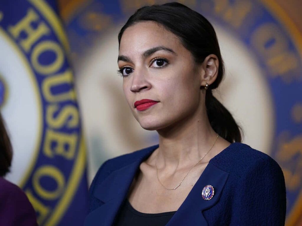 Alexandria Ocasio-Cortez confident professional portrait blue backdrop determination wallpaper