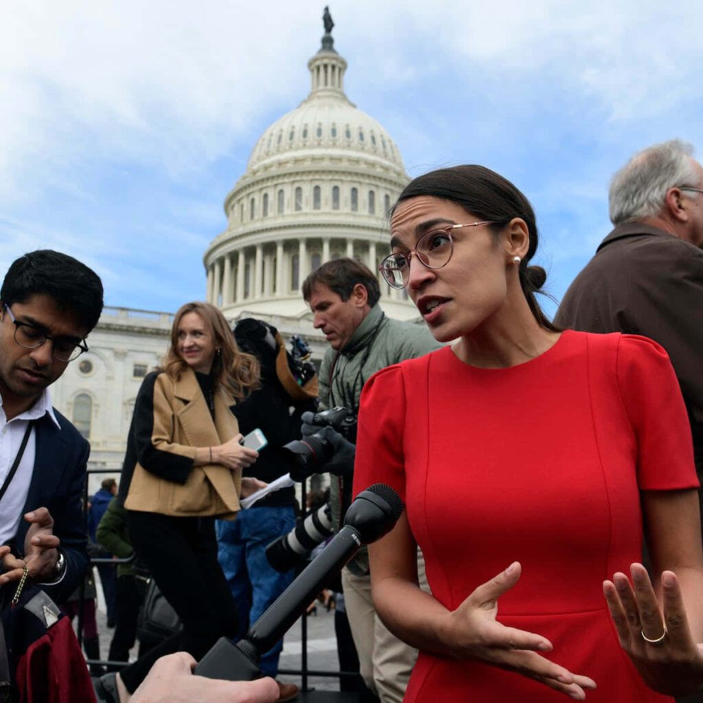 Alexandria Ocasio-Cortez speaking passionately during an interview outside the US Capitol building Wallpaper