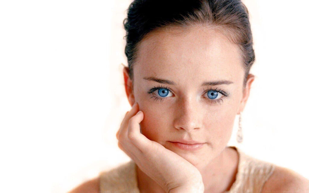 Alexis Bledel thoughtful gaze with striking blue eyes and calm expression on soft light background Wallpaper