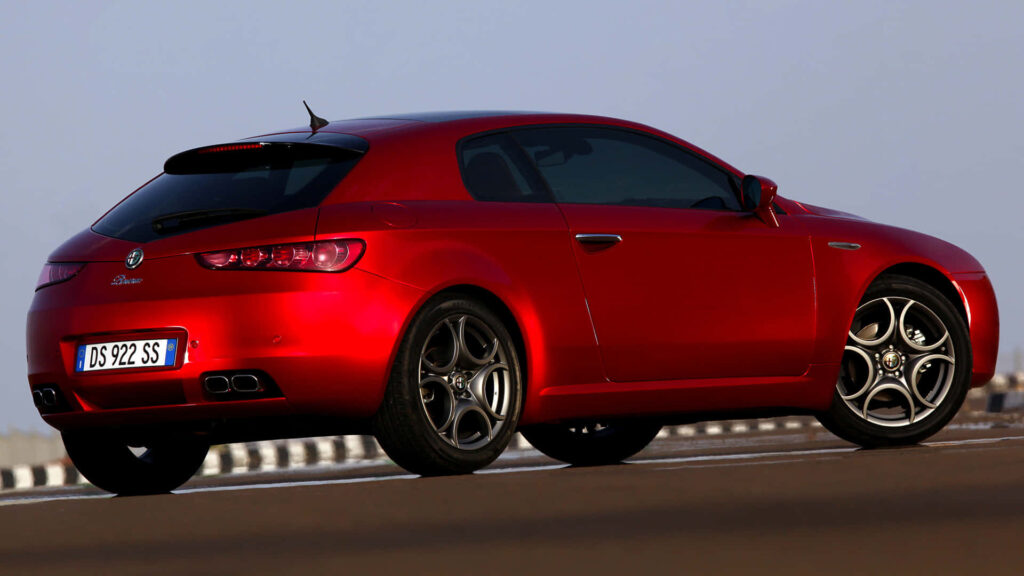 Alfa Romeo Brera red sports car with sleek curves in vibrant outdoor clear sky background Wallpaper