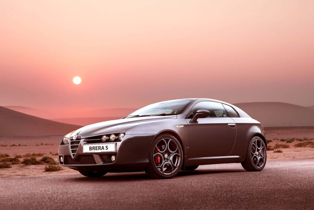 Alfa Romeo Brera on empty road at sunset with warm light and dramatic shadows wallpaper background