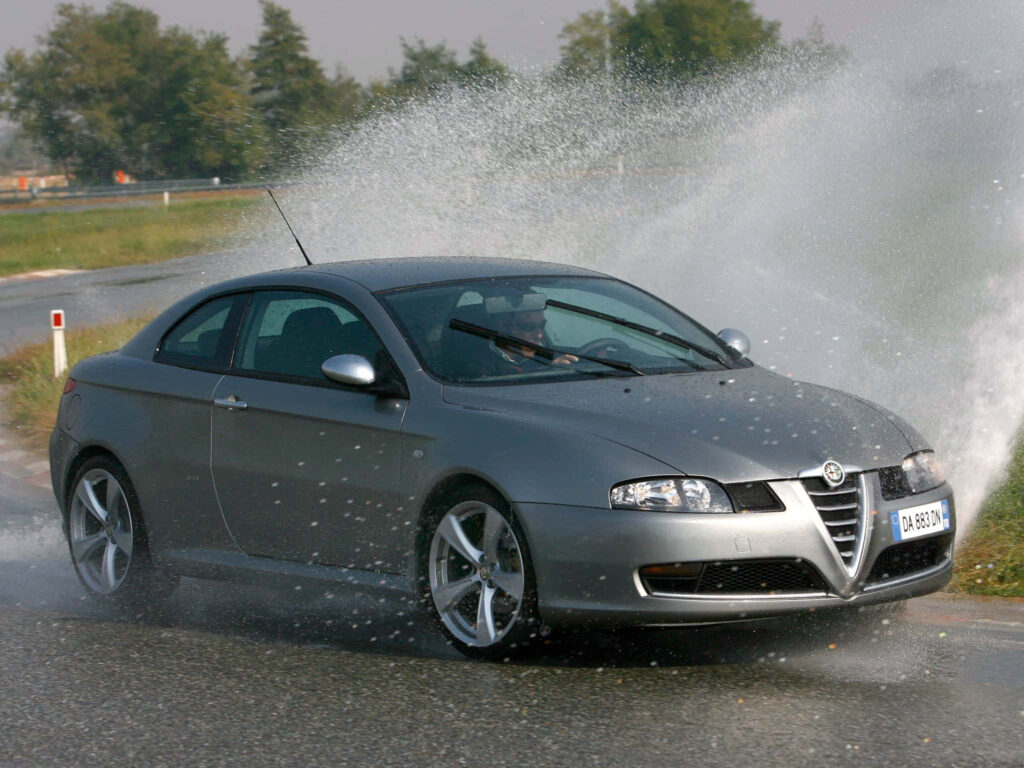 Alfa Romeo GT speeding on wet racetrack with water spray dynamic thrilling car wallpaper