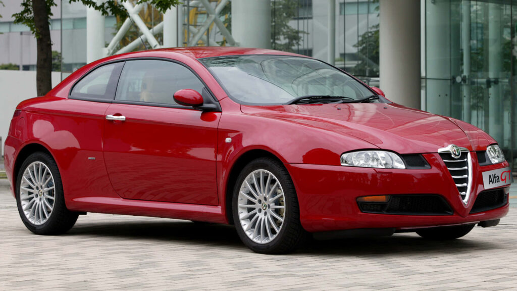 Red Alfa Romeo GT with elegant curves against a modern urban backdrop wallpaper background