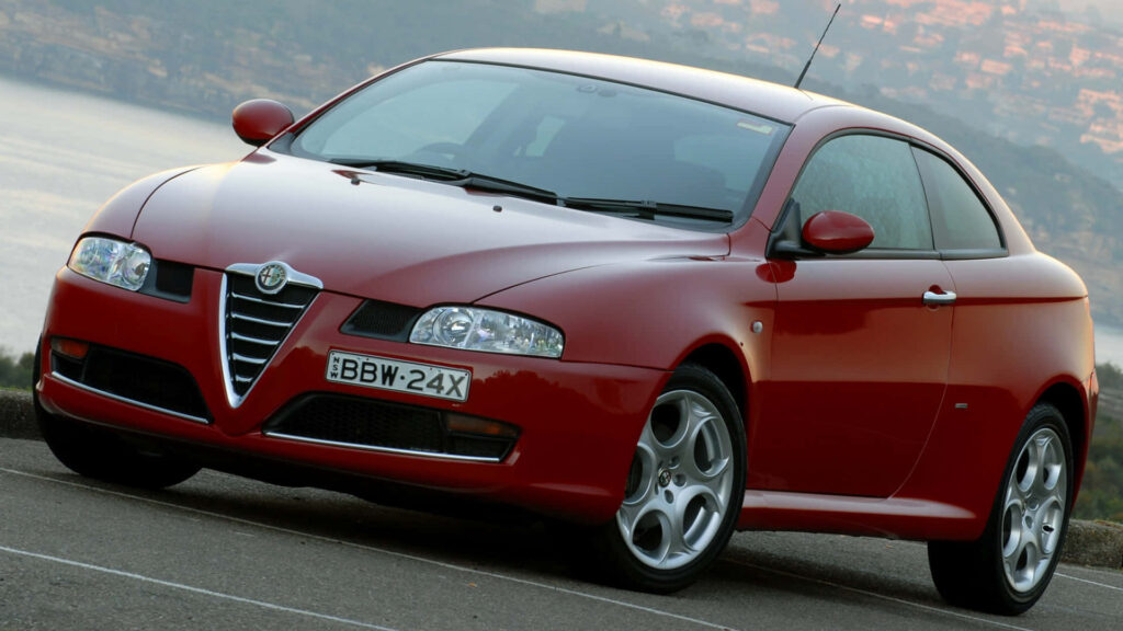 Alfa Romeo GT sports car parked overlooking scenic landscape featuring bold curves and grille Wallpaper