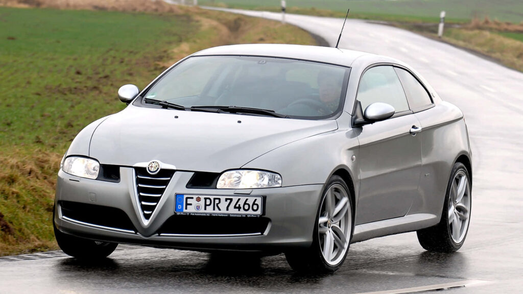 Alfa Romeo GT sporty car driving on wet city street showcasing sleek modern design wallpaper