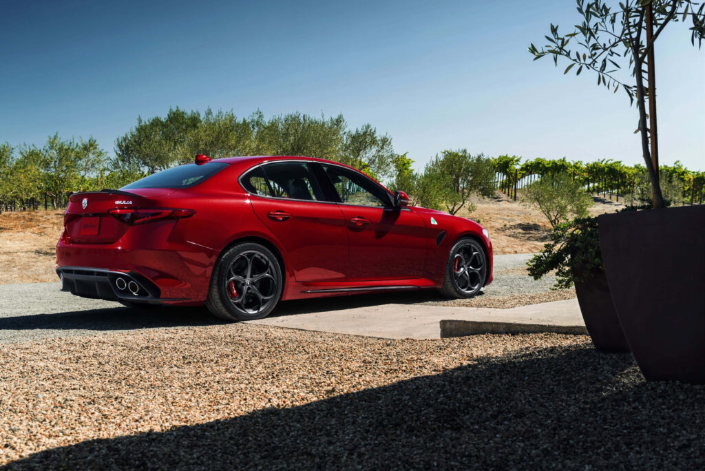Alfa Romeo Giulia deep red parked on scenic road with lush greenery and clear blue skies wallpaper