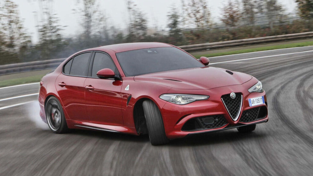 Alfa Romeo Giulia Quadrifoglio speeding on racetrack dynamic design sleek performance wallpaper