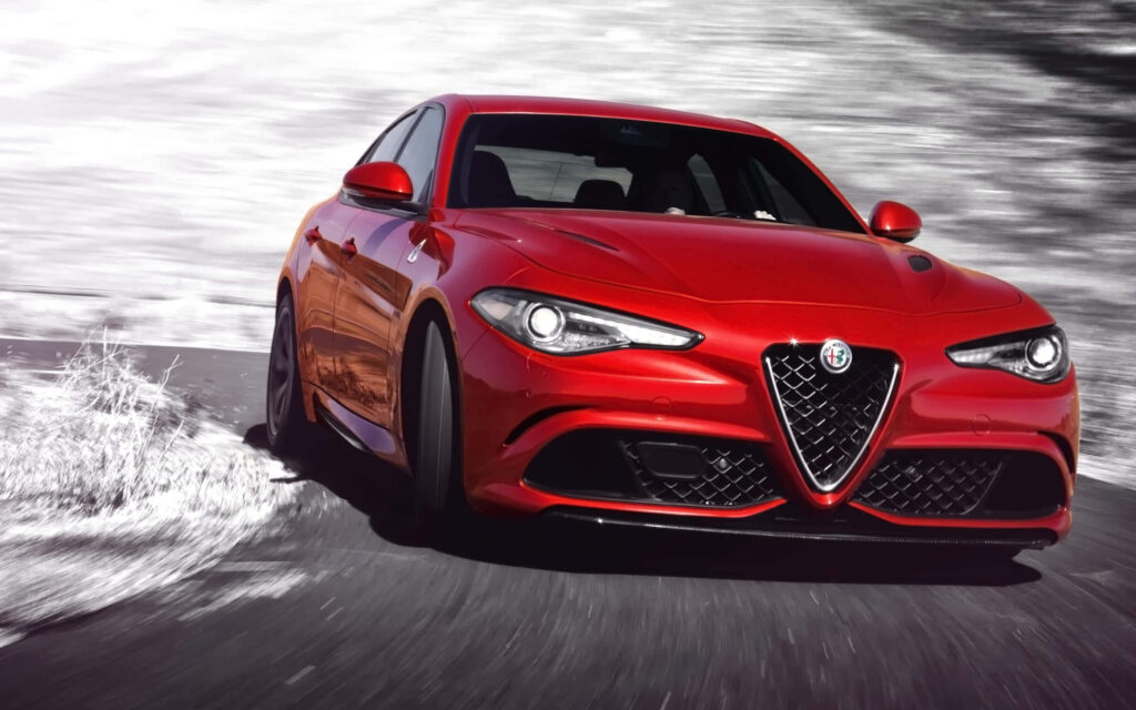 Alfa Romeo Giulia red sports car in motion with signature grille on blurred road background Wallpaper