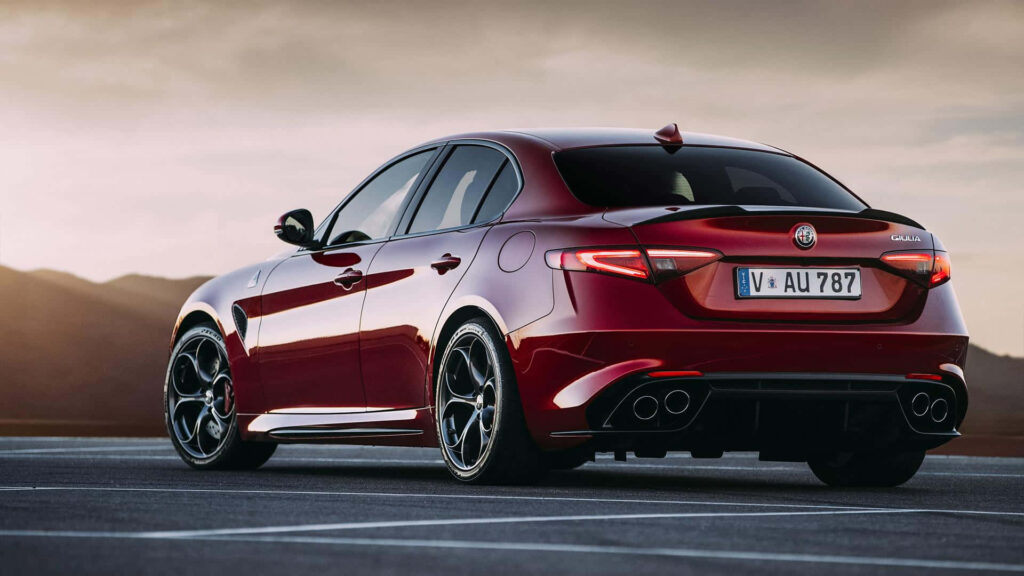 Red Alfa Romeo Giulia driving fast with sporty design and mountain scenery in background wallpaper