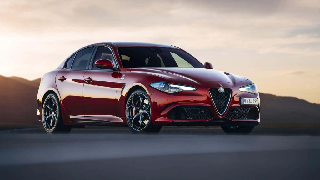 Alfa Romeo Giulia speeding on open road with dramatic sunset sky wallpaper background