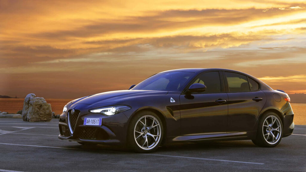 Alfa Romeo Giulia parked with vibrant sunset skyline and scenic background wallpaper
