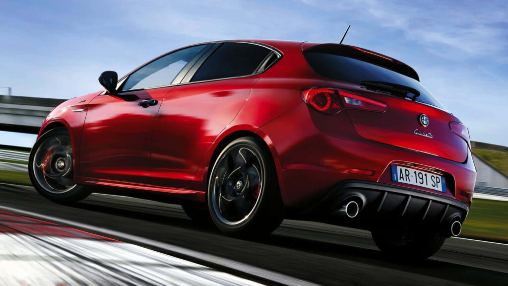 Red Alfa Romeo Giulietta speeding on road showcasing sporty design and dynamic presence Wallpaper