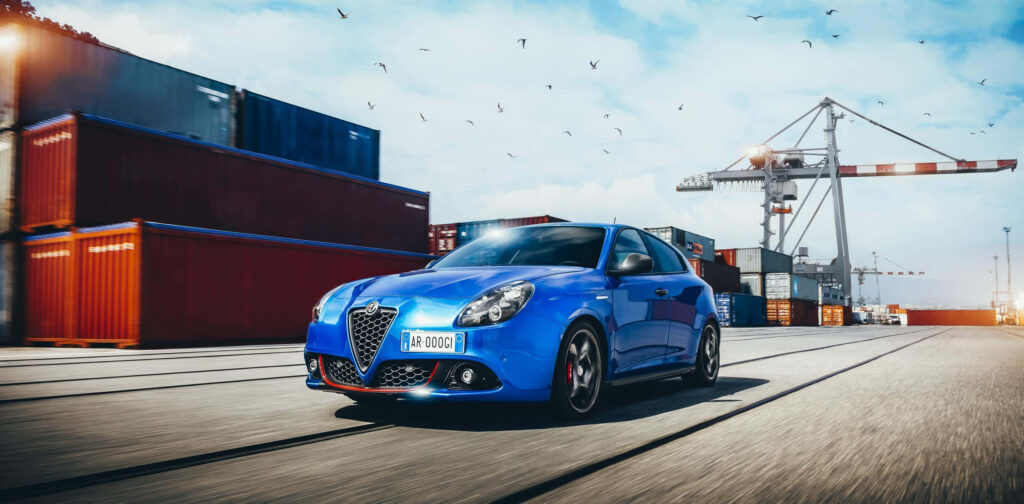 Alfa Romeo Giulietta parked by colorful shipping containers with cranes urban adventure wallpaper