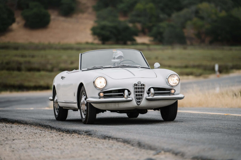 Classic Alfa Romeo Spider driving on scenic countryside road showcasing elegant timeless design Wallpaper