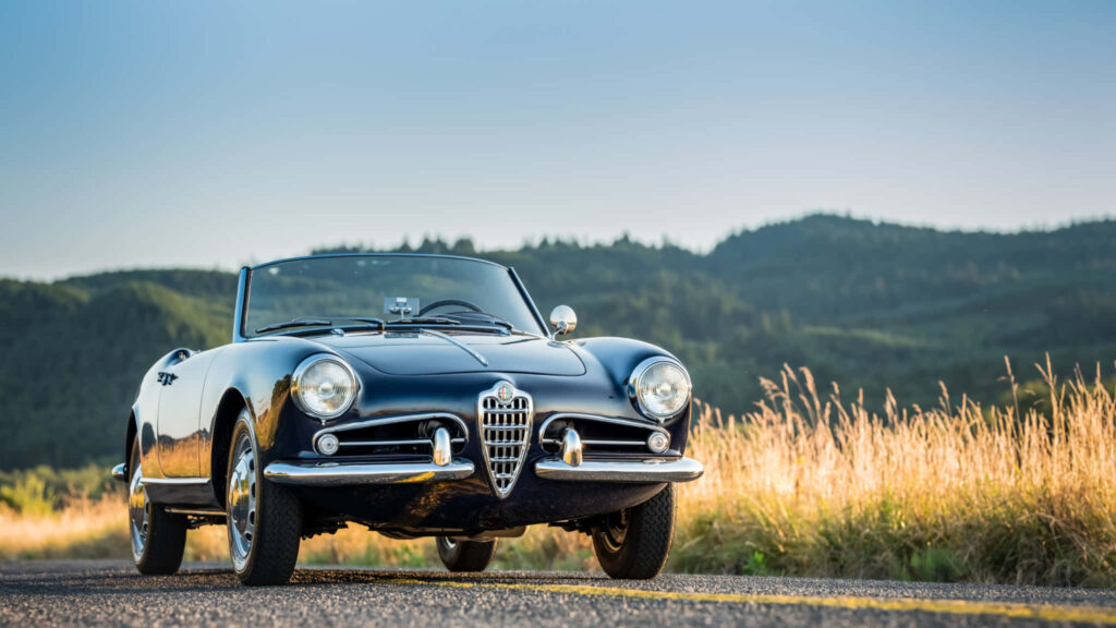 Alfa Romeo Spider convertible with black finish on open road at sunset showcasing classic curves Wallpaper