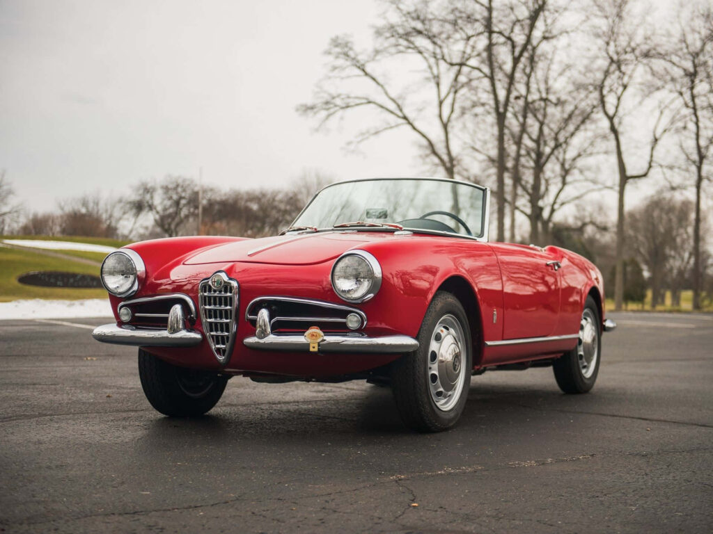 Alfa Romeo Spider parked on quiet road with scenic bare trees and open fields under calm sky Wallpaper