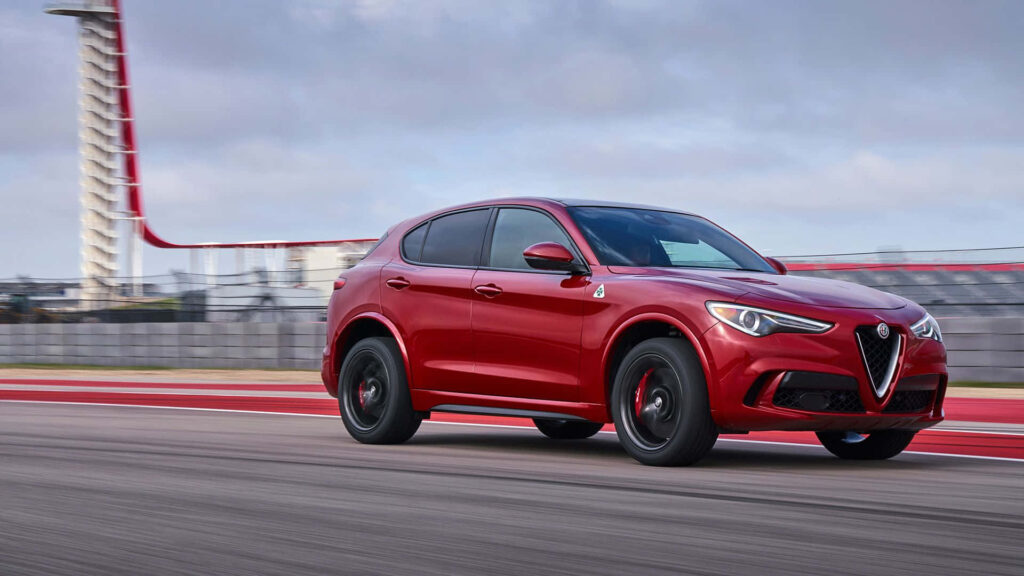 Red Alfa Romeo Stelvio driving on scenic mountain road vibrant dynamic wallpaper background
