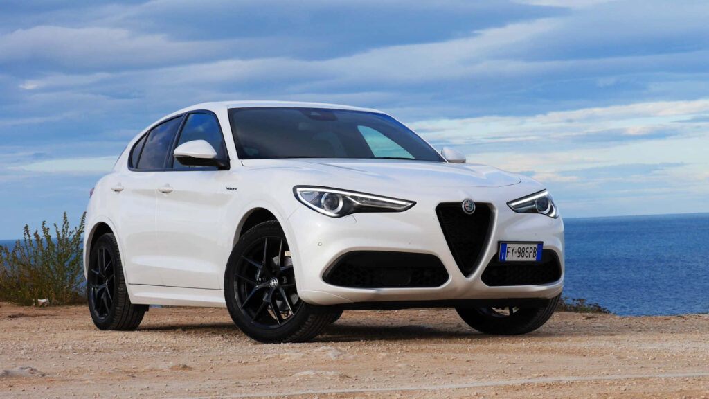 White Alfa Romeo Stelvio parked by scenic coastal road showcasing sleek luxury SUV design Wallpaper
