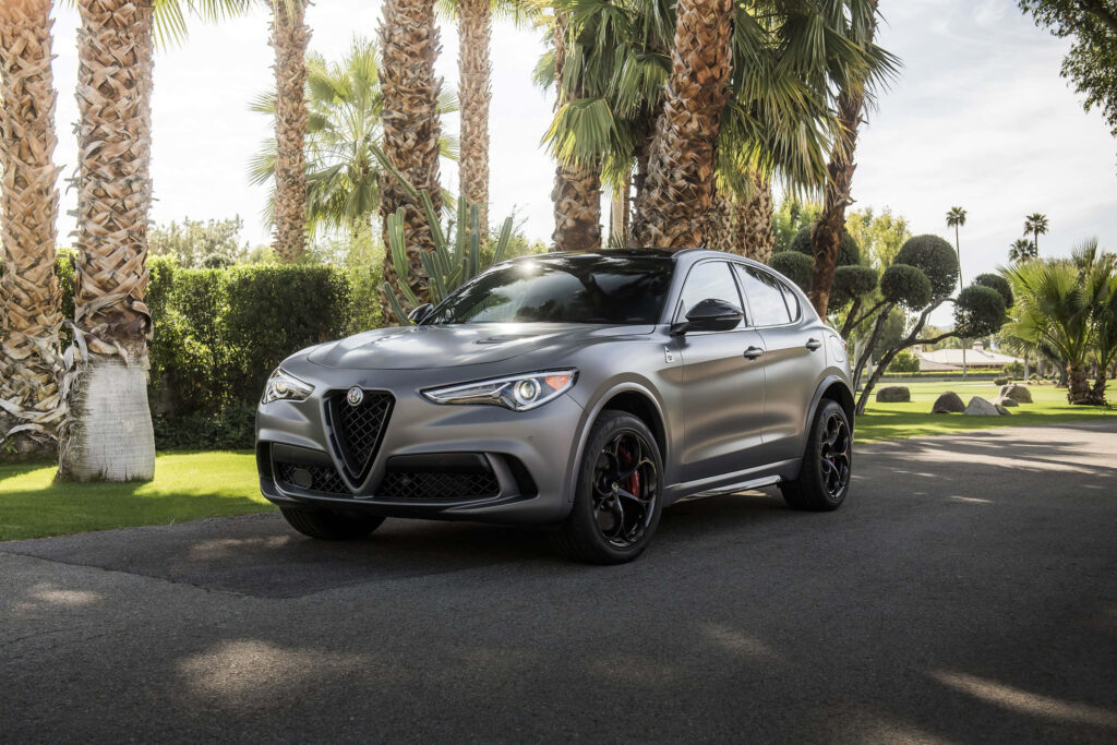 Alfa Romeo Stelvio parked on scenic route with lush palm trees and vibrant green foliage background Wallpaper