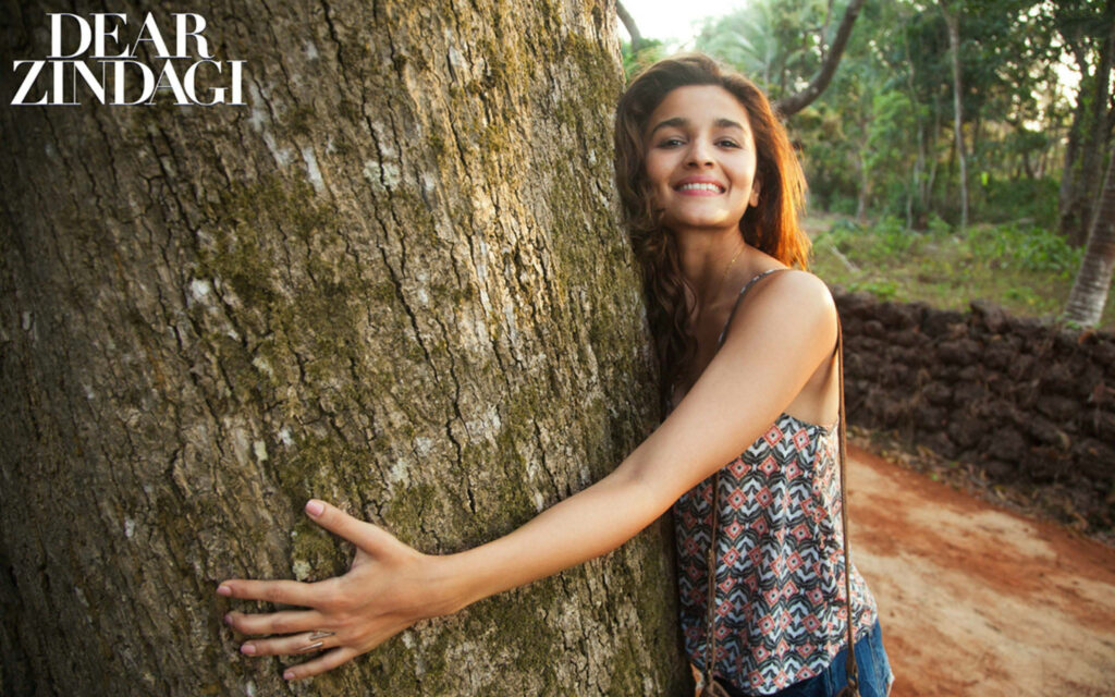 Alia Bhatt smiling warmly hugging a tree outdoors joyful scene Dear Zindagi wallpaper background